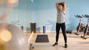 Person stretching in a gym environment after a workout, highlighting post-workout recovery strategies
