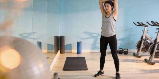 Person stretching in a gym environment after a workout, highlighting post-workout recovery strategies