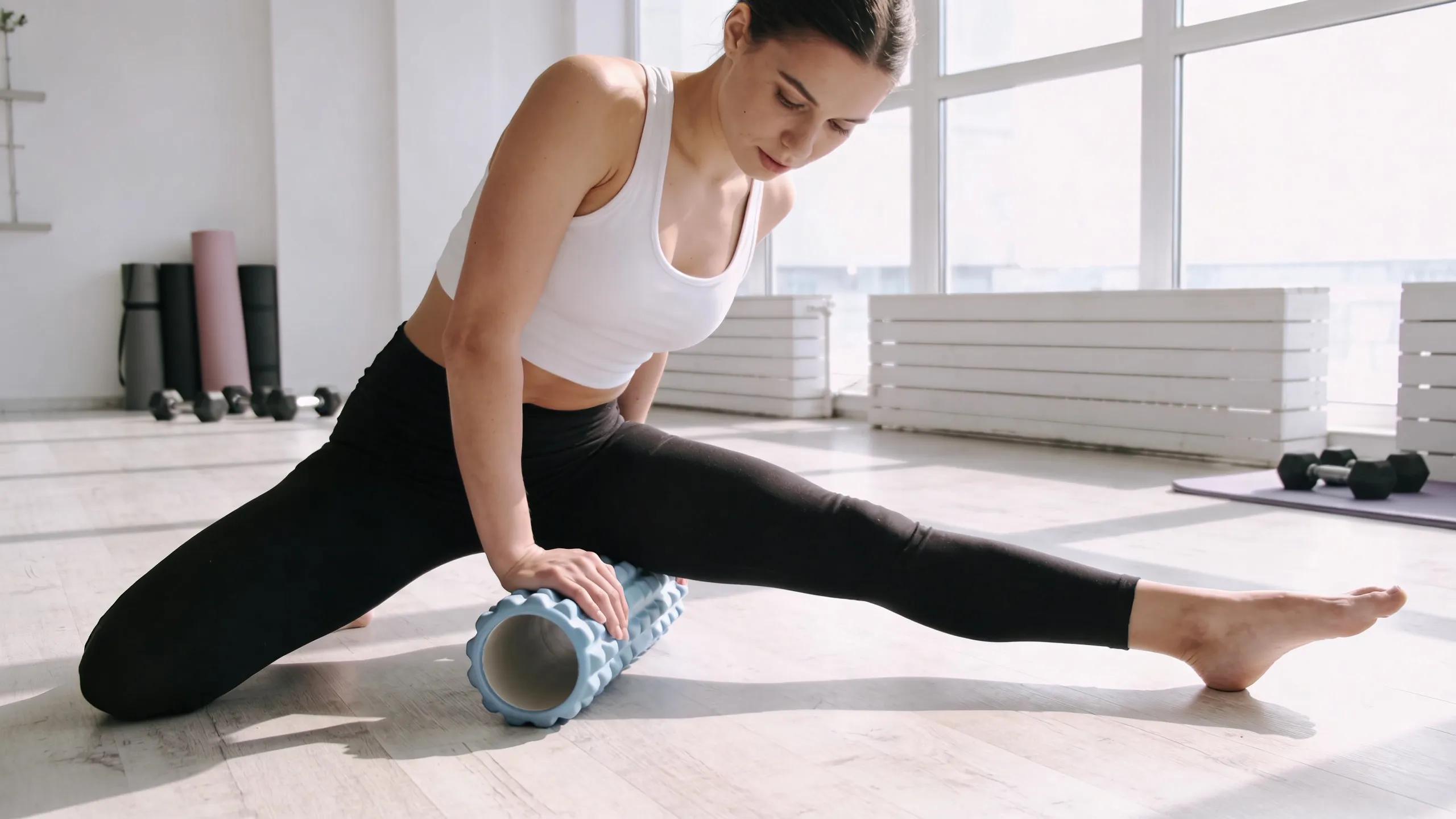 Person using a foam roller in a fitness studio to relieve muscle tightness